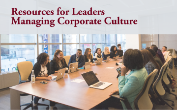A business meeting with diverse group of participants sitting at a conference table with laptops and notebooks engaging in a conversation